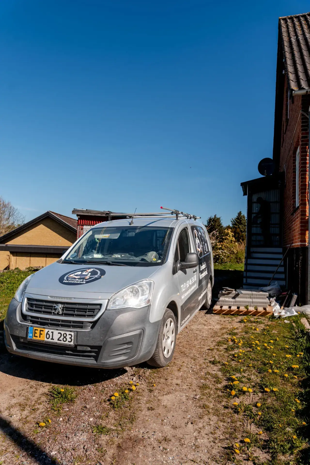 Lundbak's Varmetekniks firmabil parkeret ved et hus i solskin